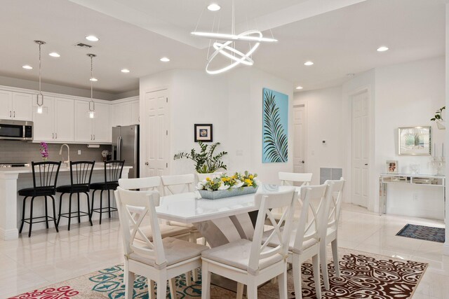 kitchen with a kitchen island with sink, white cabinetry, stainless steel appliances, and decorative light fixtures