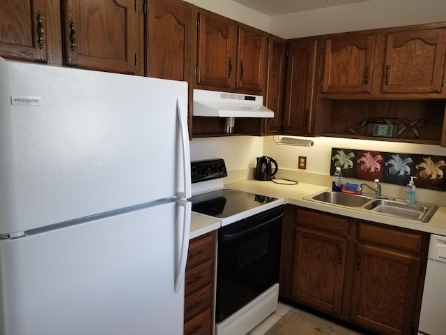 kitchen featuring a textured ceiling, white appliances, and sink