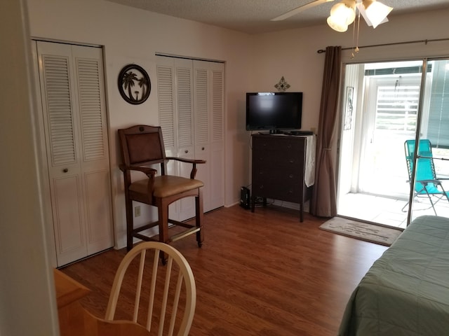 bedroom featuring wood-type flooring, multiple closets, ceiling fan, and a textured ceiling