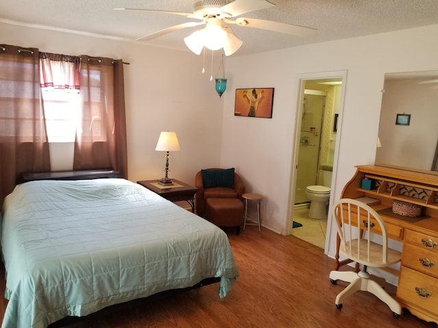 bedroom with a textured ceiling, connected bathroom, hardwood / wood-style floors, and ceiling fan