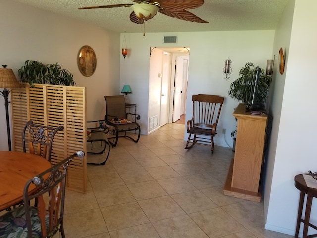 living area featuring ceiling fan, a textured ceiling, and light tile patterned floors