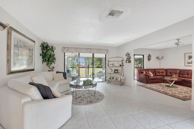 living room with ceiling fan, light tile patterned flooring, and a textured ceiling