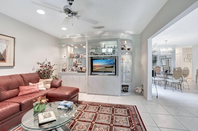 living room featuring ceiling fan with notable chandelier, a textured ceiling, and light tile patterned flooring