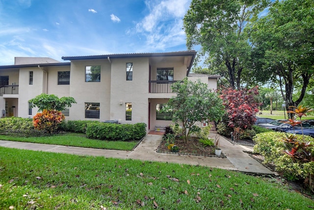 view of front of property with a front yard and a balcony