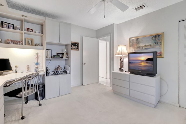 office space featuring ceiling fan, light colored carpet, and a textured ceiling