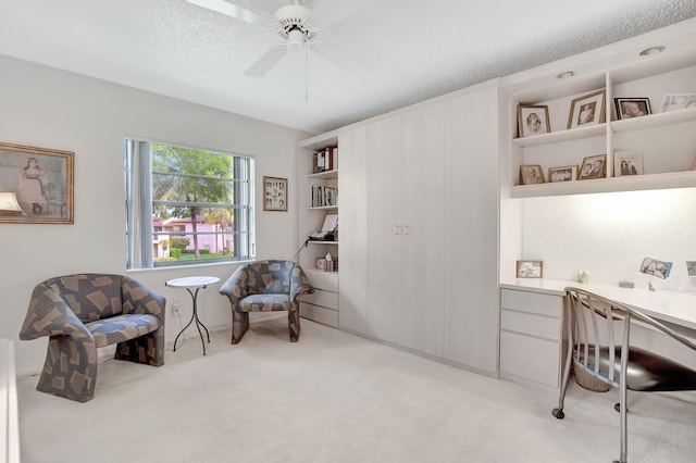 interior space featuring a textured ceiling, light carpet, and ceiling fan