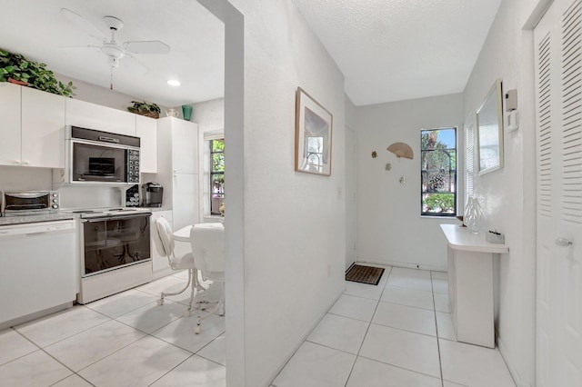 kitchen with ceiling fan, light tile patterned flooring, white appliances, a textured ceiling, and white cabinetry