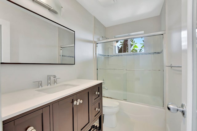 full bathroom featuring enclosed tub / shower combo, vanity, and toilet