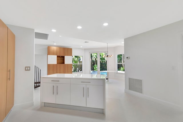 kitchen with hanging light fixtures, a chandelier, a center island, white cabinets, and french doors