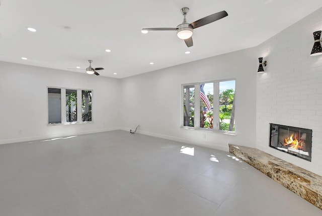 unfurnished living room with a brick fireplace and ceiling fan