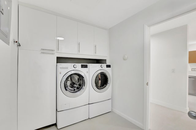 clothes washing area featuring cabinets and washing machine and dryer