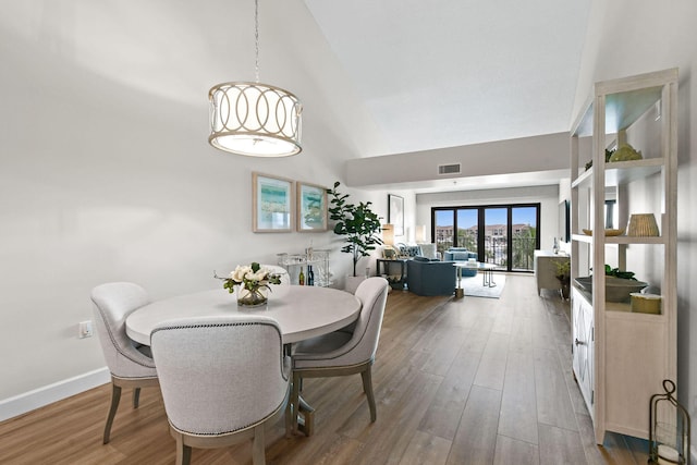 dining room with french doors, a towering ceiling, and hardwood / wood-style flooring