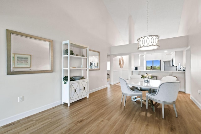 dining room with light hardwood / wood-style floors and high vaulted ceiling