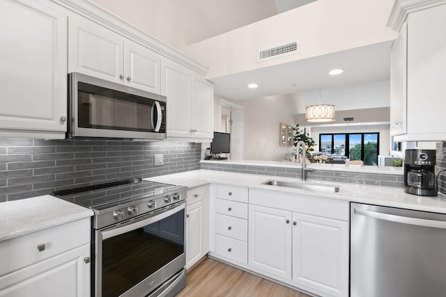 kitchen featuring sink, appliances with stainless steel finishes, decorative backsplash, white cabinets, and light wood-type flooring