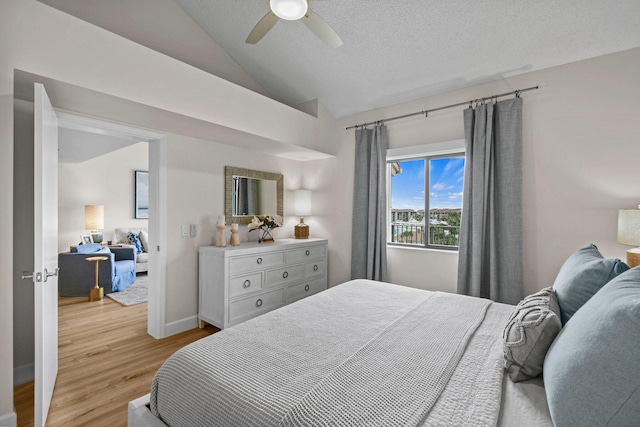 bedroom with a textured ceiling, light hardwood / wood-style floors, vaulted ceiling, and ceiling fan