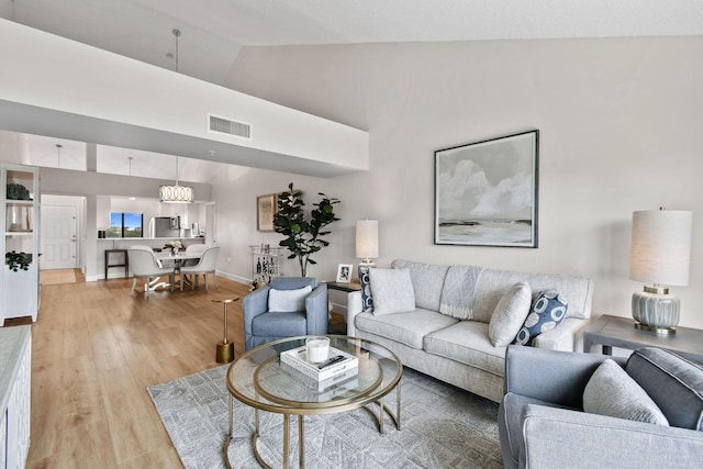 living room featuring a notable chandelier, lofted ceiling, and hardwood / wood-style flooring