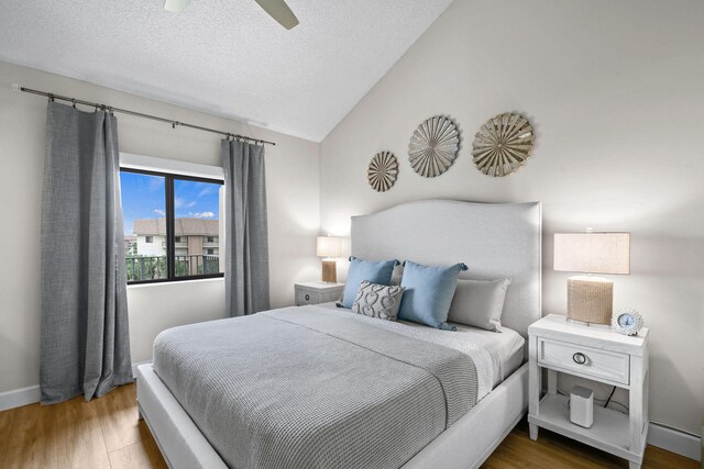 bedroom featuring ceiling fan, wood-type flooring, a textured ceiling, and lofted ceiling