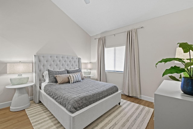 bedroom with ceiling fan, wood-type flooring, and lofted ceiling