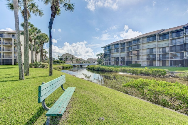 view of property's community featuring a lawn and a water view