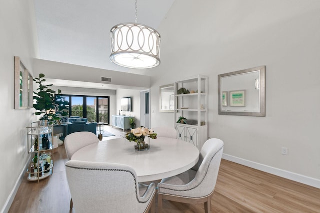 dining area featuring a towering ceiling and light hardwood / wood-style floors