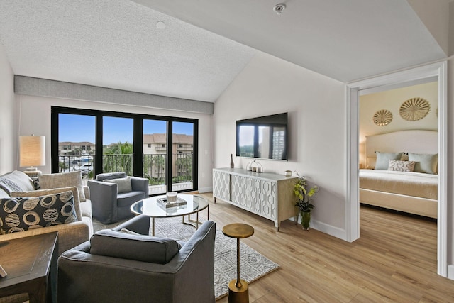 living room with lofted ceiling, light wood-type flooring, and a textured ceiling