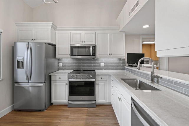 kitchen featuring backsplash, stainless steel appliances, sink, light hardwood / wood-style floors, and white cabinetry