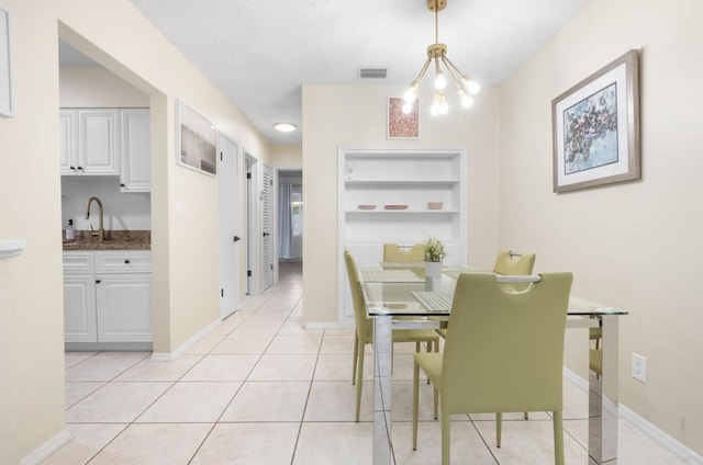 dining space featuring light tile patterned floors, a textured ceiling, built in shelves, sink, and a notable chandelier