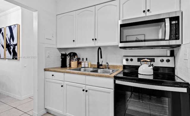 kitchen featuring sink, white cabinetry, stainless steel appliances, backsplash, and light tile patterned floors