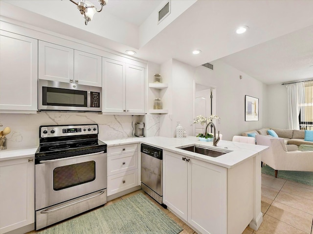 kitchen featuring kitchen peninsula, appliances with stainless steel finishes, white cabinets, and sink