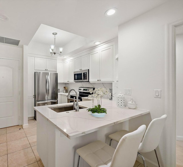 kitchen with kitchen peninsula, stainless steel appliances, hanging light fixtures, and a breakfast bar area