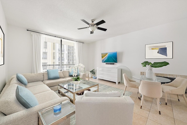 living room featuring ceiling fan, light tile patterned floors, and a textured ceiling