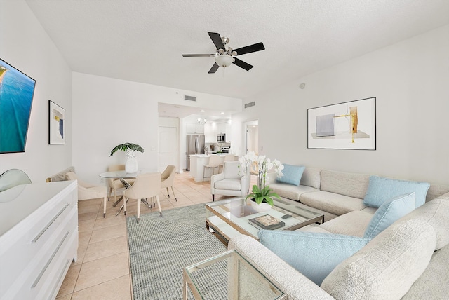 living room featuring ceiling fan, light tile patterned flooring, and a textured ceiling