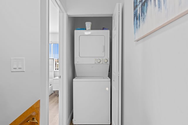 laundry room with wood-type flooring and stacked washer and dryer