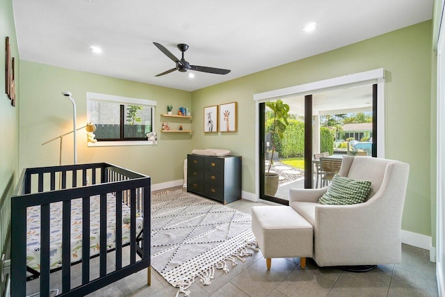 bedroom with ceiling fan, light tile patterned flooring, a crib, and multiple windows