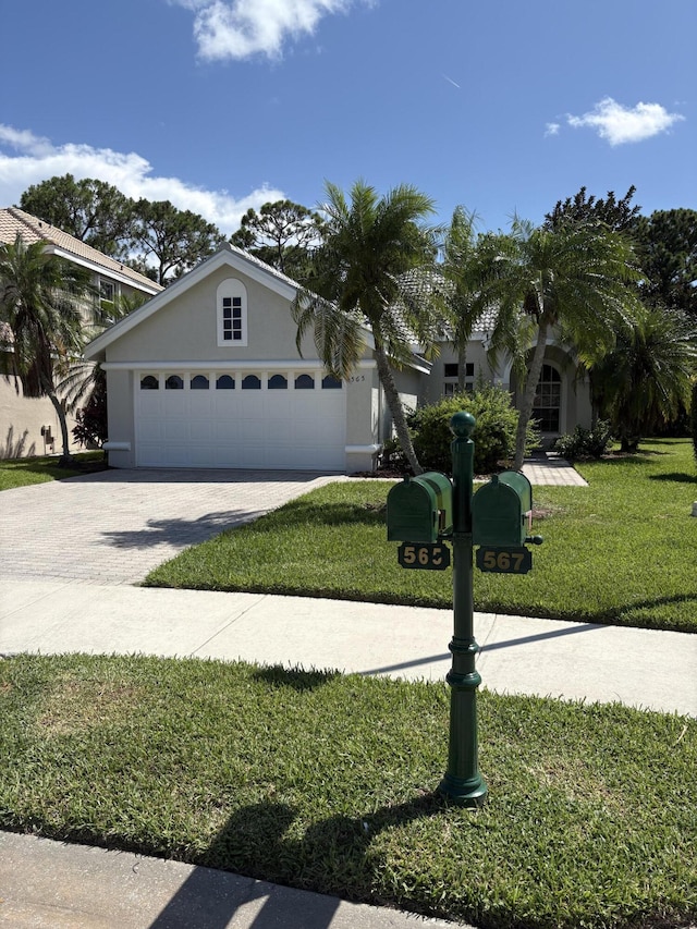 565 SW New Castle Cv, Port Saint Lucie, FL 34986 - view of front of house with stucco siding, a front yard, driveway, and a garage