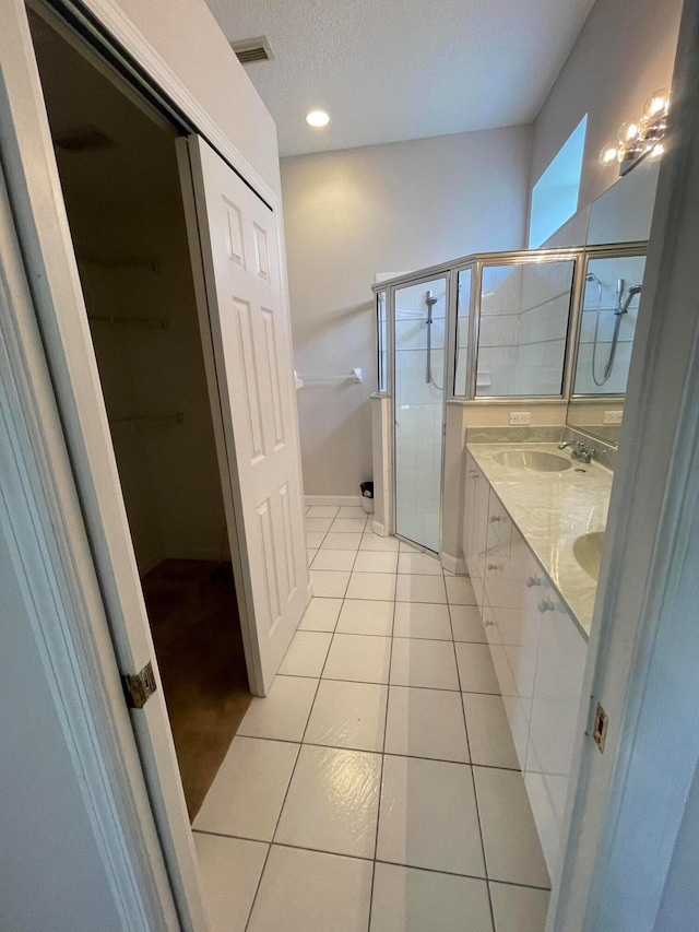 bathroom featuring vanity, a textured ceiling, tile patterned flooring, and an enclosed shower