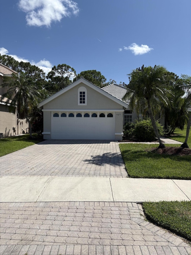 565 SW New Castle Cv, Port Saint Lucie, FL 34986 - view of front facade featuring decorative driveway, a garage, and stucco siding