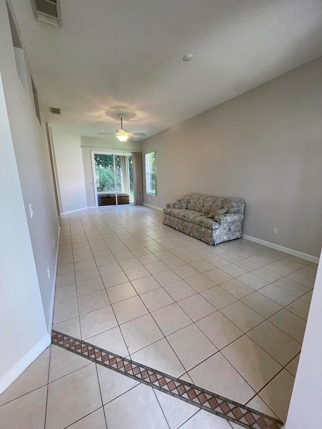 unfurnished living room with a textured ceiling, light tile patterned floors, and ceiling fan