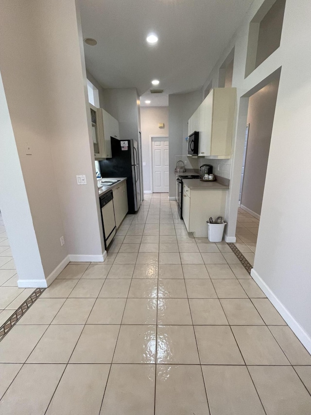 565 SW New Castle Cv, Port Saint Lucie, FL 34986 - kitchen with black microwave, light tile patterned floors, freestanding refrigerator, recessed lighting, and dishwasher