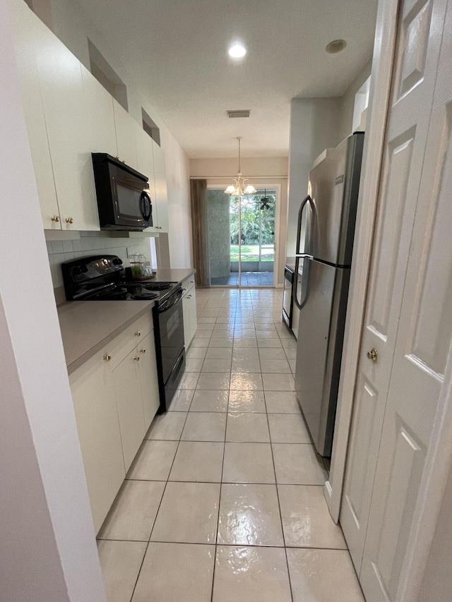 565 SW New Castle Cv, Port Saint Lucie, FL 34986 - kitchen with black appliances, white cabinetry, light tile patterned flooring, a chandelier, and recessed lighting