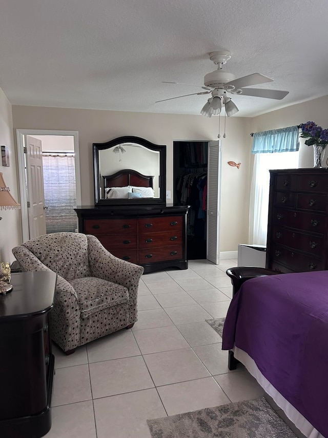 tiled bedroom with a closet, ceiling fan, and a textured ceiling