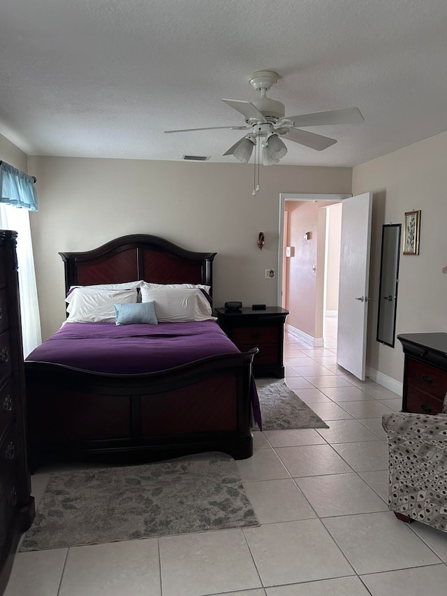 bedroom with ceiling fan, light tile patterned flooring, and a textured ceiling