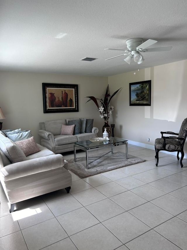 living room featuring ceiling fan, light tile patterned flooring, and a textured ceiling