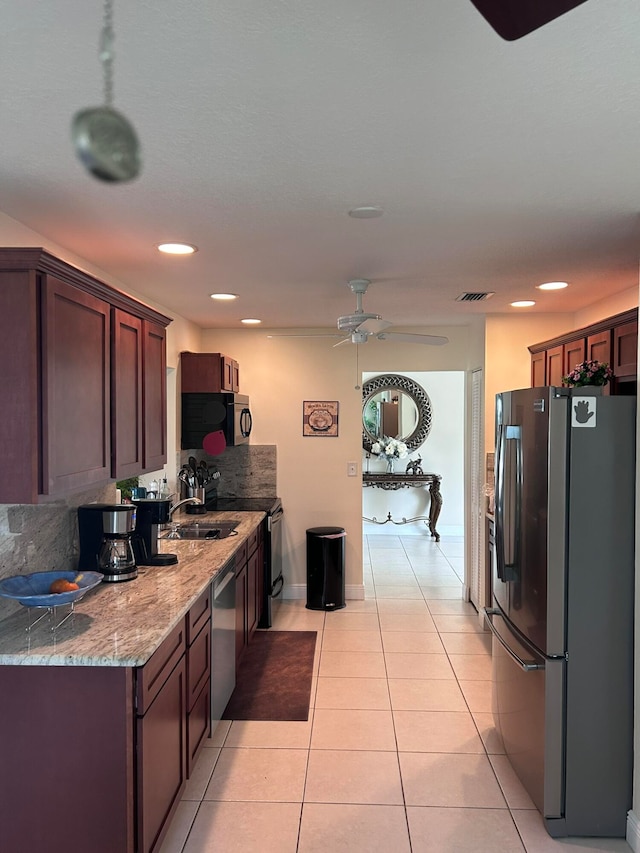 kitchen with tasteful backsplash, light stone countertops, light tile patterned floors, stainless steel appliances, and ceiling fan