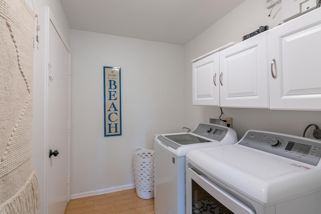 laundry room with washer and clothes dryer, light hardwood / wood-style floors, and cabinets