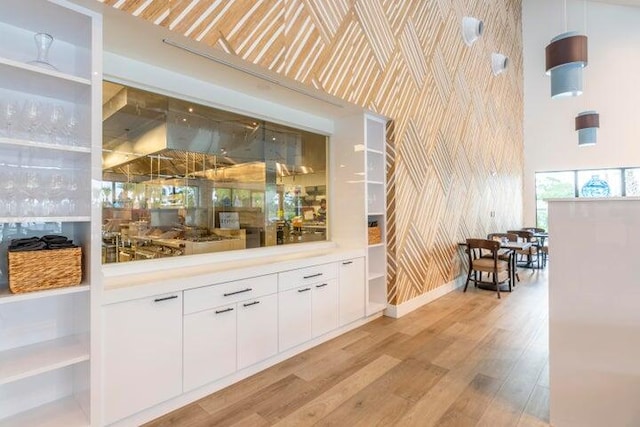 bar featuring white cabinets, lofted ceiling, and light hardwood / wood-style flooring