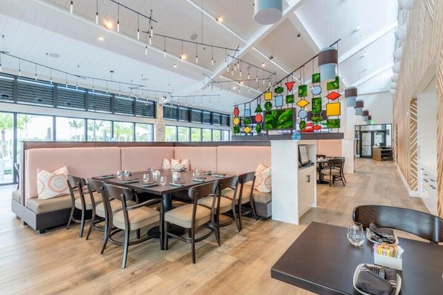 dining space with light wood-type flooring and a towering ceiling