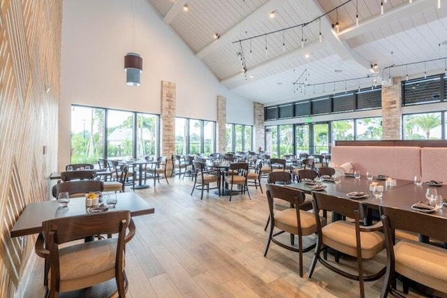 dining space with plenty of natural light, light wood-type flooring, wood ceiling, and high vaulted ceiling