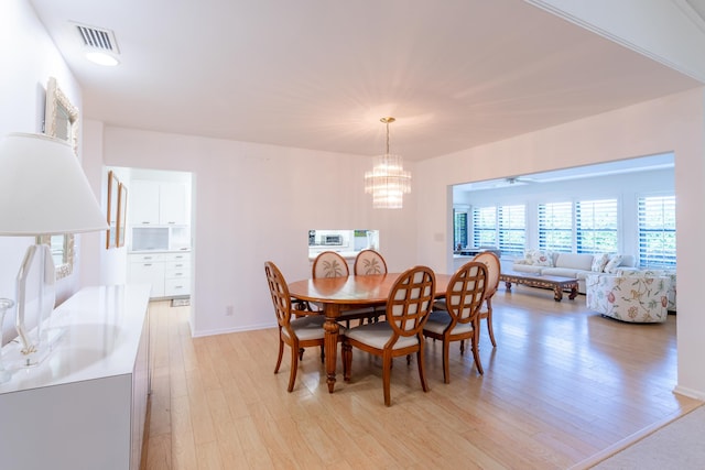 dining space featuring ceiling fan with notable chandelier and light wood-type flooring