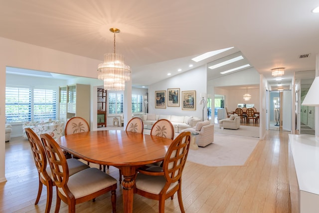 dining room featuring light hardwood / wood-style flooring, lofted ceiling with skylight, and a notable chandelier